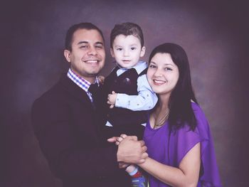 Portrait of happy family standing against gray background