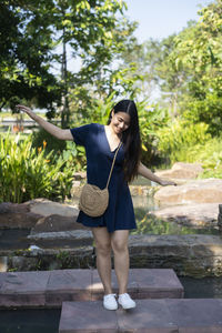 Full length of young woman standing against trees