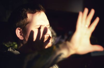 Close-up of young man shielding eyes at home