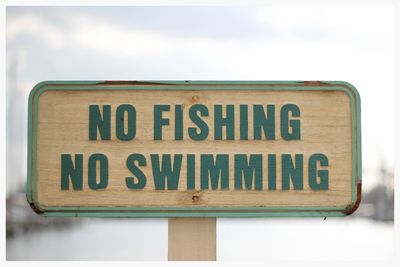 Close-up of road sign against white wall