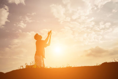 Low angle view of silhouette man standing on field against sky during sunset