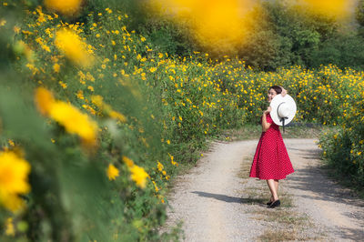 Woman standing by flowers on field