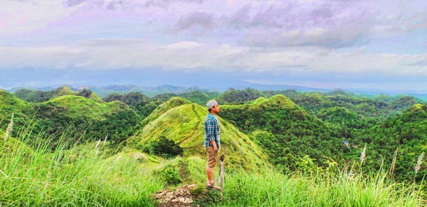 Rear view of man standing in farm against sky