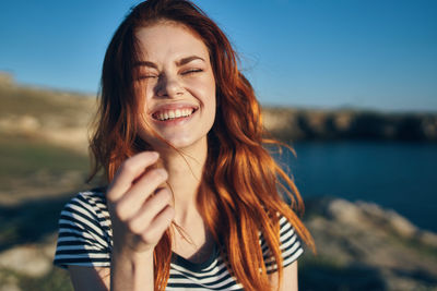 Portrait of smiling young woman against sky