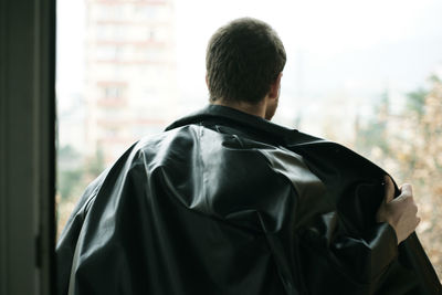 Rear view of man standing against window