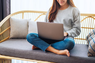 Midsection of woman using laptop at home