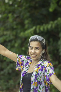 Portrait of smiling woman standing against trees