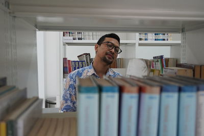 Young man seen through book shelf