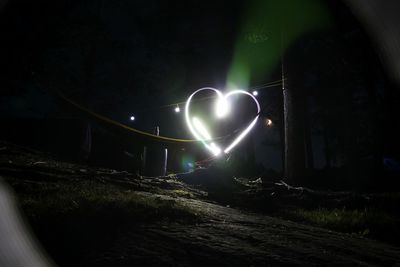 Light trails on illuminated street in forest at night
