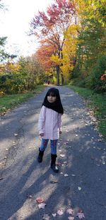 Portrait of girl on road amidst plants during autumn