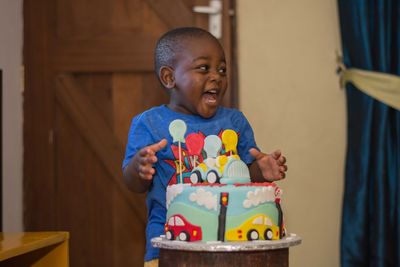 Cheerful boy with birthday cake at home