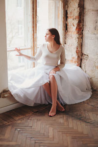 Young woman looking away while sitting on floor