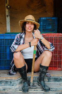 Full length of woman wearing hat sitting outdoors