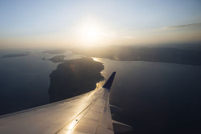 Airplane wing over landscape against sky