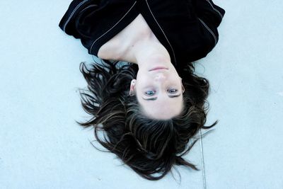 High angle portrait of young woman lying on snow field