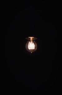 Low angle view of illuminated light bulb in darkroom