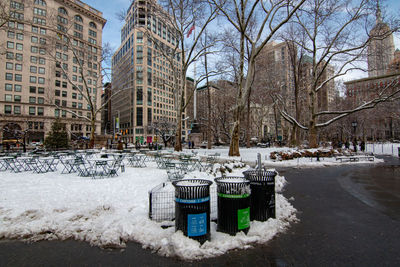 Snow covered garbage bin against buildings in city