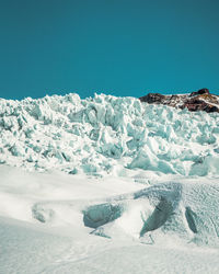 Snow covered landscape against blue sky