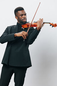 Young man holding violin against white background