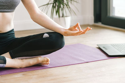 Close-up of girl's hands practicing yoga at home. a girl sits on a yoga mat in a lotus position 