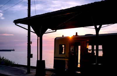 Silhouette built structure by sea against sky during sunset