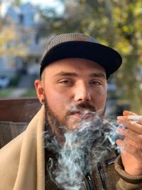Portrait of man smoking cigarette in city