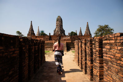 Rear view of woman walking towards temple old ruins