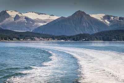 Scenic view of sea by mountains against sky