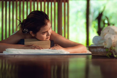 Woman looking away while lying on table in spa