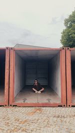 Full length portrait of woman sitting outdoors alone 