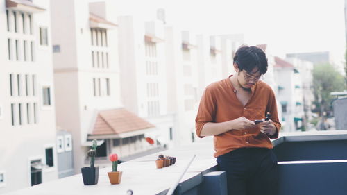 Young man using mobile phone while standing outdoors