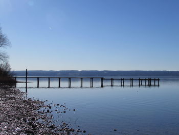 Pier over lake against clear blue sky