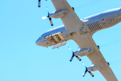 Low angle view of airplane flying against clear blue sky