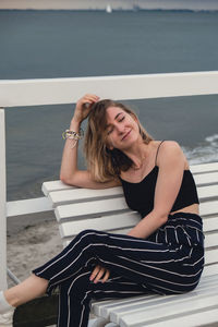 Portrait of young woman sitting on railing