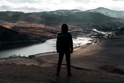 Rear view of man standing on mountain against sky