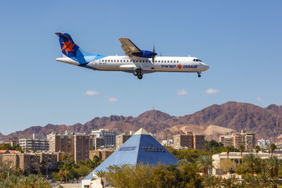 Airplane flying over buildings against clear blue sky