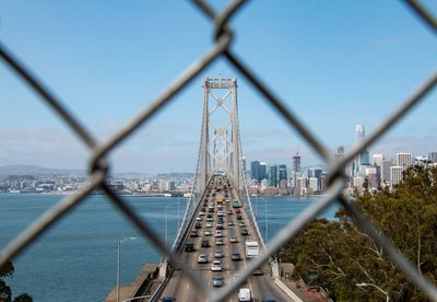 San francisco-oakland bay bridge over sea seen through chainlink fence