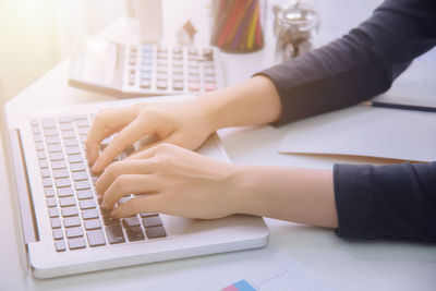 Midsection of woman using laptop on table