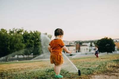 Rear view of boy playing with water sprinklers