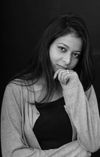 Portrait of smiling young woman against black background