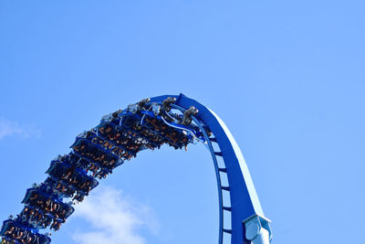 Low angle view of rollercoaster against clear blue sky