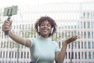 Young afro-haired student sitting on the campus stairs on a video call with her relatives