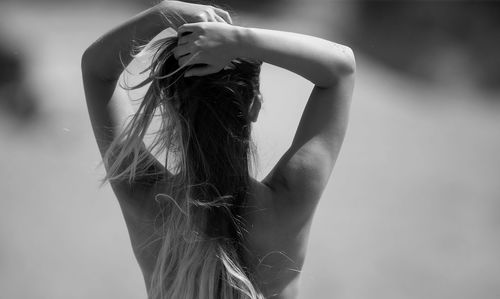 Rear view of woman with arms raised standing outdoors