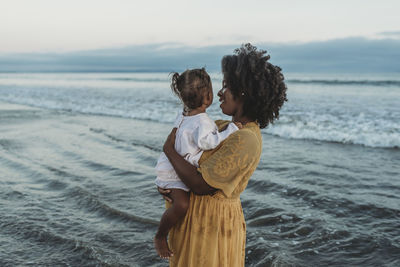 Side view of mother and daughter embracing in the ocean