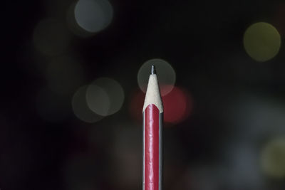 Close-up of pencil against illuminated lights