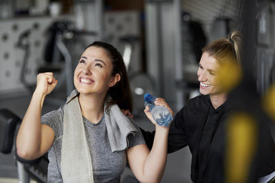 Trainer looking at cheerful woman in gym