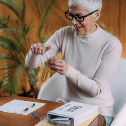 Midsection of woman holding paper while sitting on table