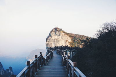 Footpath leading towards mountains against clear sky