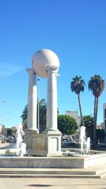 Fountain in front of building against blue sky