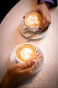 Cropped hands of friends having cappuccino served on table